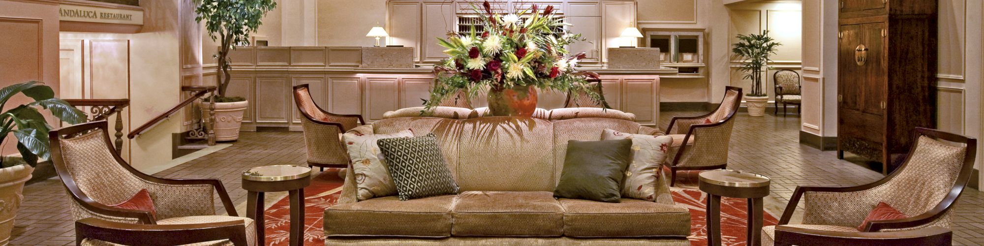 A luxurious hotel lobby with a seating area, chandeliers, plants, and a reception desk in the background. Top it at 140 characters, always ending the sentence.