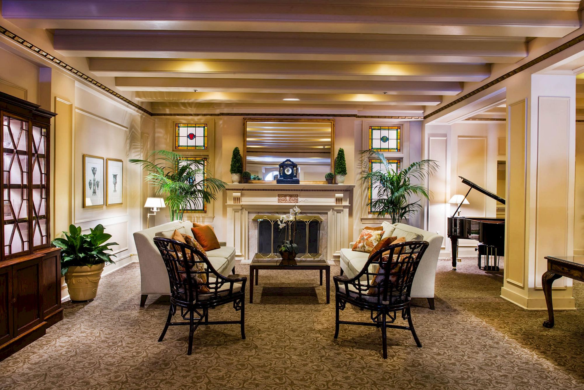 A cozy seating area in a historic Seattle hotel featuring a central fireplace, plush armchairs, a grand piano, and warm ambient lighting.