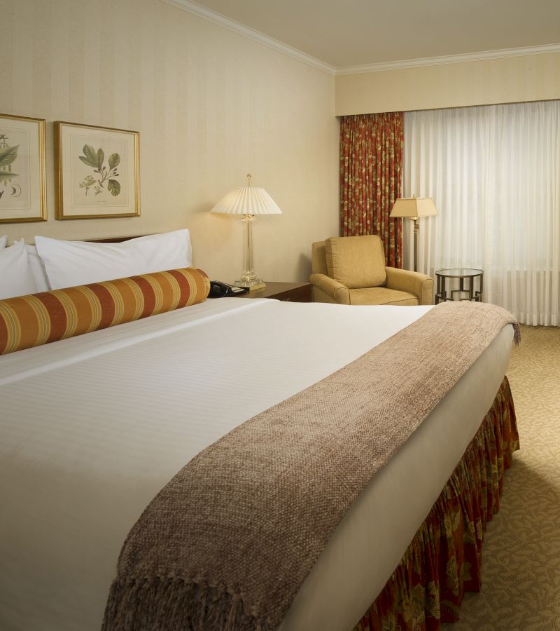 A hotel room with a large bed, chair, and window
