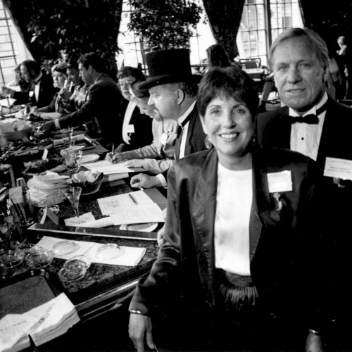 A crowded 1960s-style bar scene with black-and-white patrons, glassware, and a jukebox vibe&mdash;people chatting, standing, and smiling.