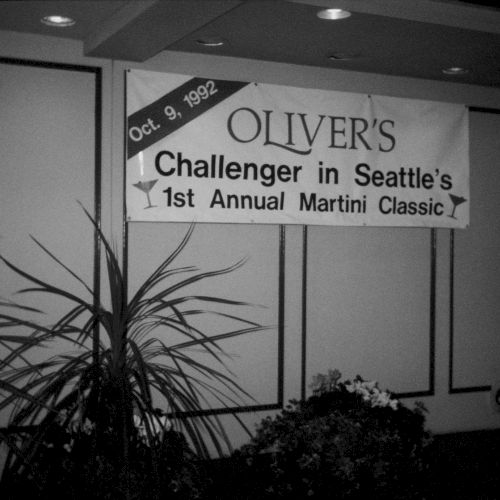 A weathered sign reads &ldquo;OLIVIUS&rdquo; on a wooden fence, with bare trees and a cloudy sky creating a moody, desolate scene.