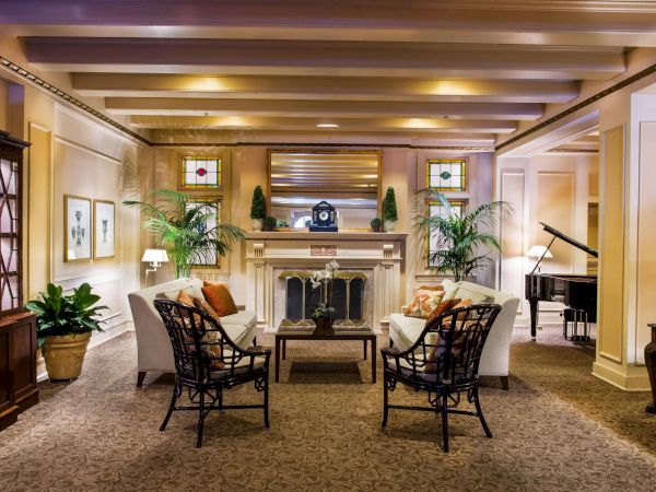 A luxurious hotel lounge with a stone fireplace, elegant seating, potted plants, warm lighting, and a grand piano in the corner, inviting relaxation.