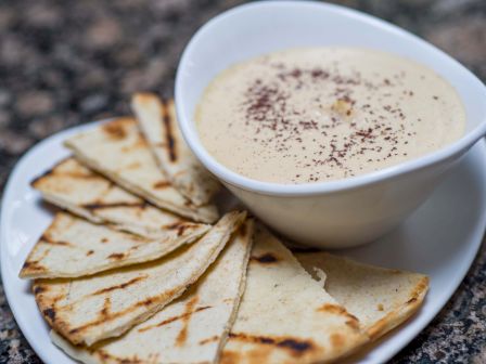 Delicious-looking flatbread with a creamy dip sprinkled with paprika, served on a white plate.