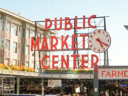 Public Market Center sign with a clock and market stalls beneath, outdoor market vibe.
