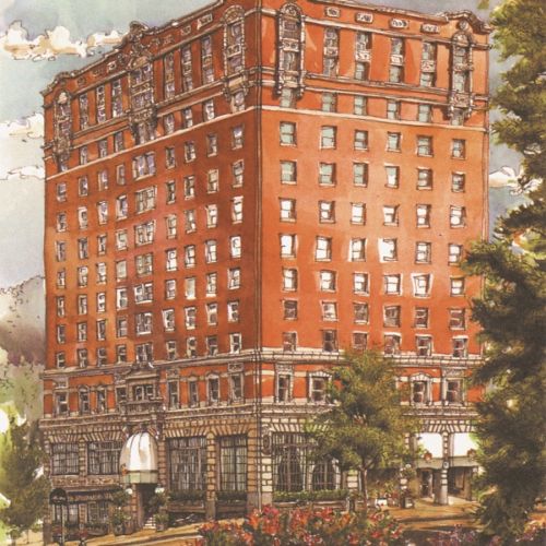 Old brick building with multiple windows and a tree-lined street in front, urban cityscape.