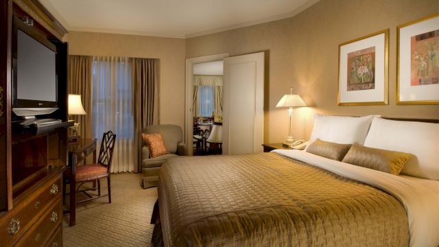 A hotel room with a large bed, TV, desk, and chair.