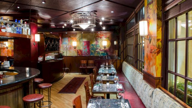 A restaurant or bar interior with booth seating, a bar, and tables set for dining.