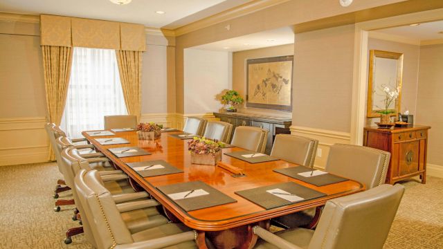 A long wooden table with leather chairs in a meeting room.
