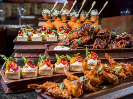 A delicious party spread: mini bites on wooden boards &mdash; skewered skewers, crispy fried shrimp, bite-sized canap&eacute;s topped with colorful garnishes; indulgent hors d'oeuvres.